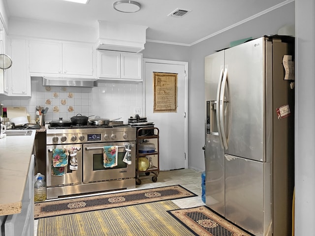 kitchen featuring white cabinets, appliances with stainless steel finishes, tasteful backsplash, and ornamental molding