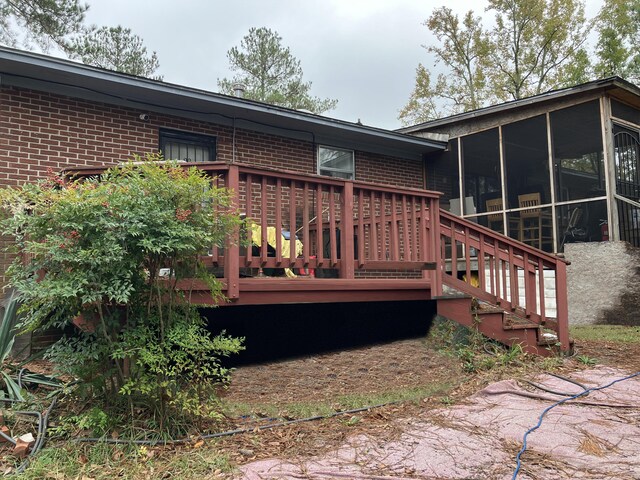 rear view of property with a sunroom and a deck