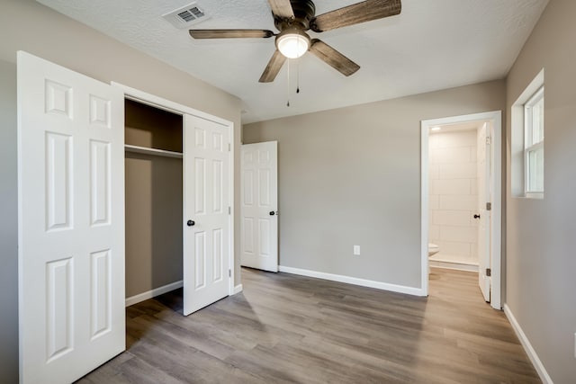 unfurnished bedroom featuring a closet, visible vents, baseboards, and wood finished floors