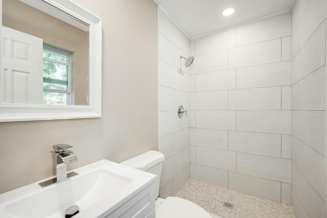 full bathroom with vanity, a tile shower, and toilet