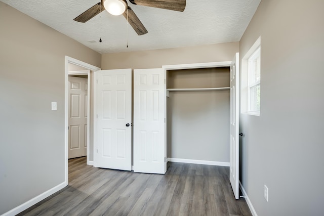 unfurnished bedroom featuring a textured ceiling, wood finished floors, a ceiling fan, baseboards, and a closet