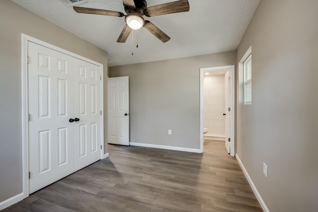 unfurnished bedroom featuring a closet, a textured ceiling, baseboards, and wood finished floors