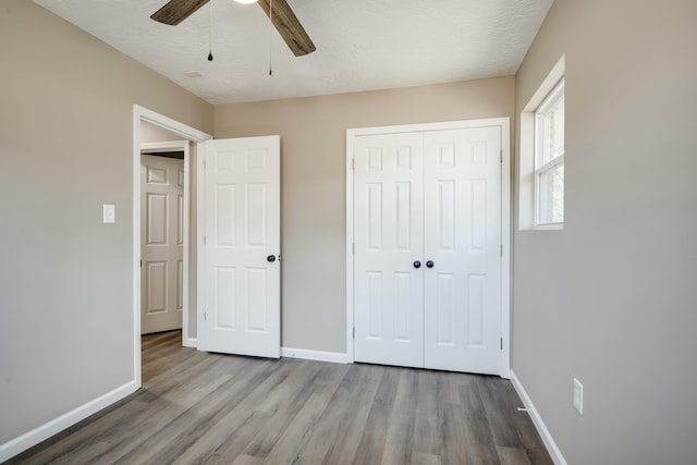 unfurnished bedroom with a textured ceiling, a closet, light wood-style flooring, and baseboards