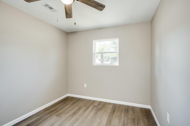 spare room featuring ceiling fan, wood finished floors, visible vents, and baseboards