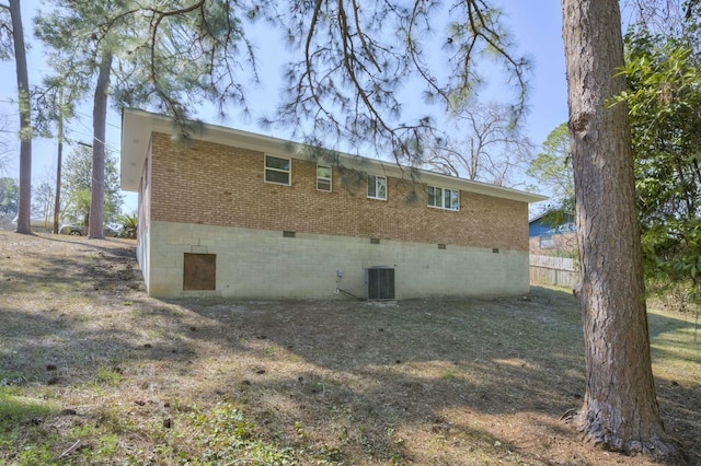 rear view of house featuring central AC, brick siding, crawl space, and fence