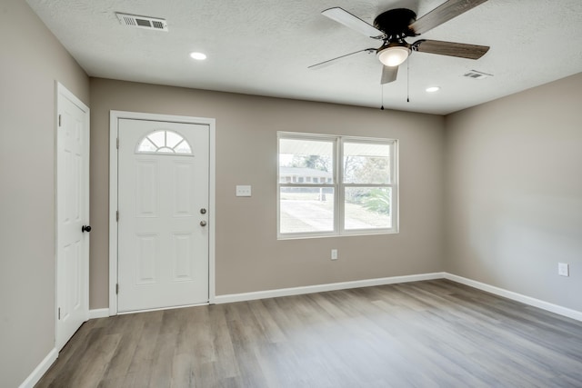 foyer entrance with light wood-type flooring, visible vents, and a textured ceiling