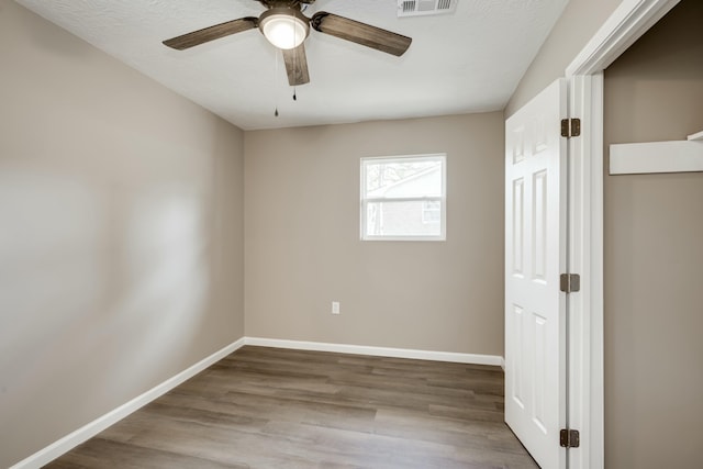 unfurnished bedroom with visible vents, ceiling fan, baseboards, and wood finished floors