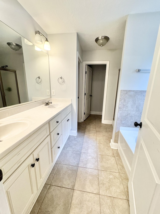 1026 Barrett Dr, Evans, GA 30809 - bathroom featuring double vanity, tile patterned floors, a shower stall, a bath, and a textured ceiling