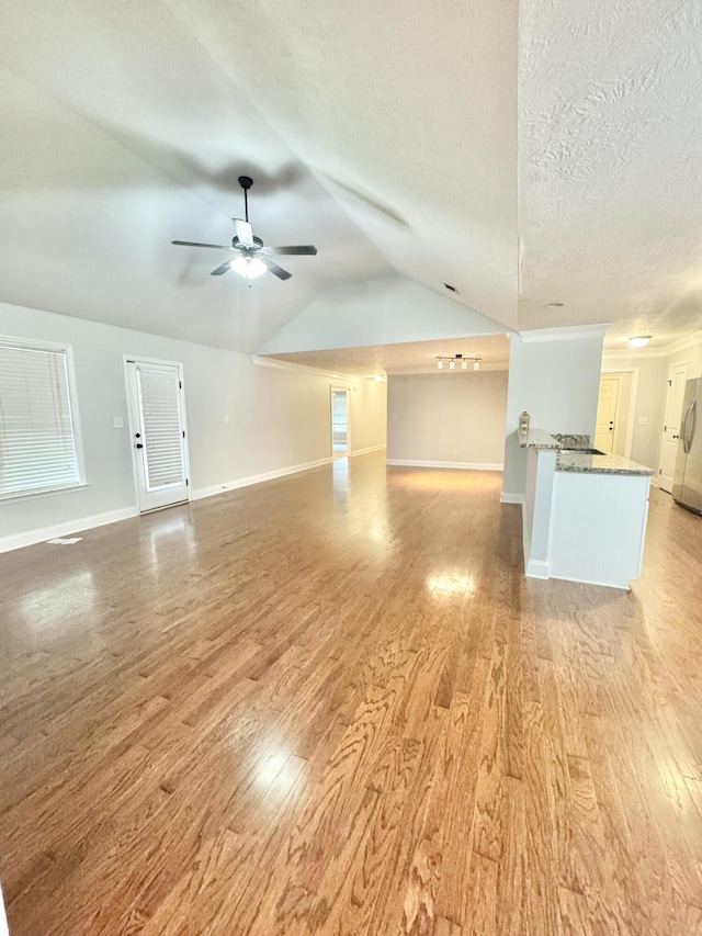 1026 Barrett Dr, Evans, GA 30809 - unfurnished living room with light wood-style floors, lofted ceiling, ceiling fan, and a textured ceiling