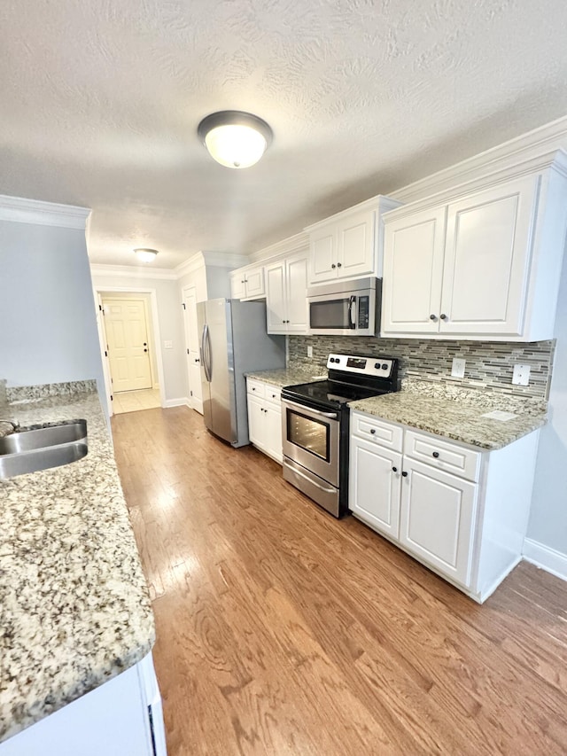 1026 Barrett Dr, Evans, GA 30809 - kitchen featuring stainless steel appliances, crown molding, white cabinets, light wood finished floors, and tasteful backsplash
