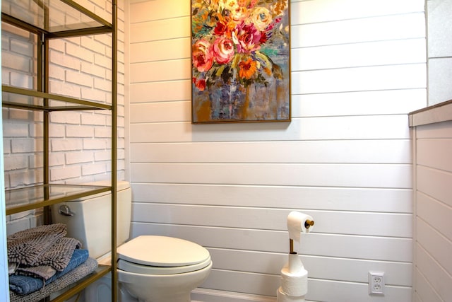 bathroom with toilet and wood walls