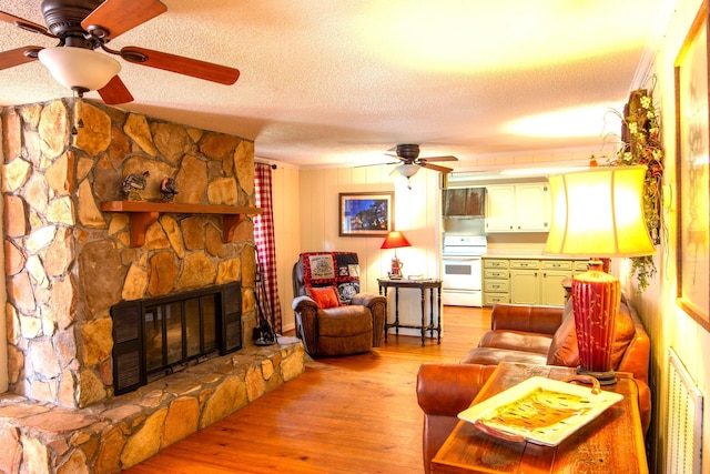 living room with a textured ceiling, ceiling fan, light hardwood / wood-style floors, and a fireplace