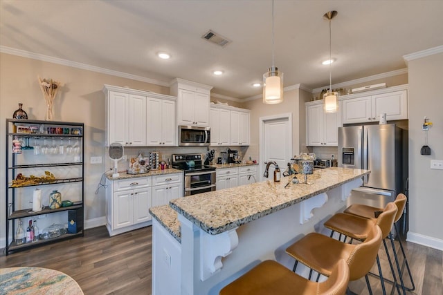 kitchen with appliances with stainless steel finishes, pendant lighting, and white cabinets