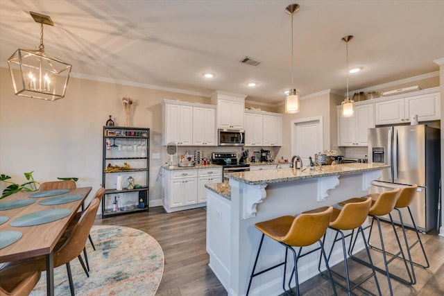 kitchen featuring a kitchen island with sink, decorative light fixtures, white cabinets, and appliances with stainless steel finishes