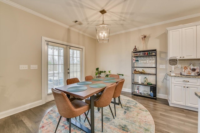 dining room featuring crown molding, light hardwood / wood-style flooring, french doors, and a chandelier