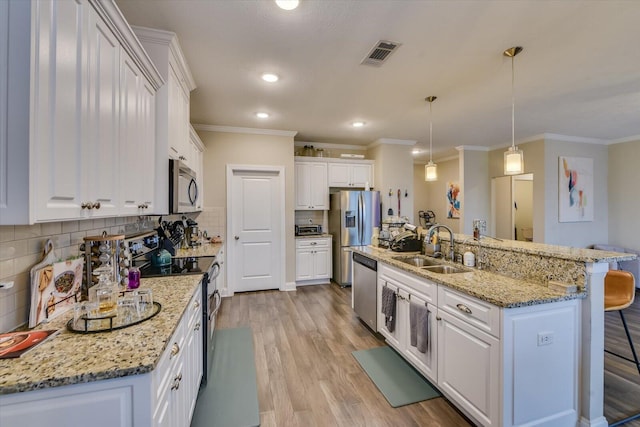 kitchen featuring stainless steel appliances, decorative light fixtures, an island with sink, and white cabinets