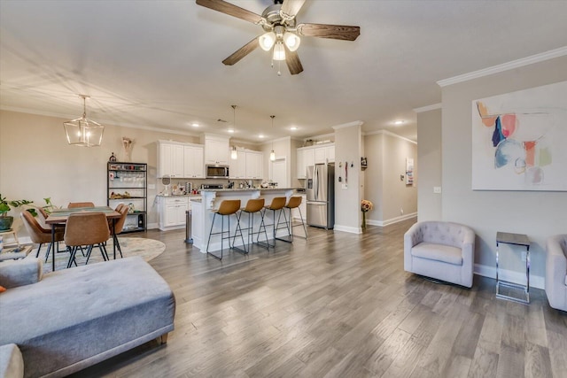 living room with crown molding, ceiling fan with notable chandelier, and light hardwood / wood-style floors