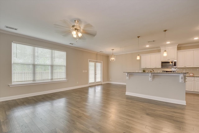 3109 Lobella Dr, Grovetown, GA 30813 - kitchen featuring stainless steel microwave, crown molding, a kitchen bar, white cabinets, and ceiling fan