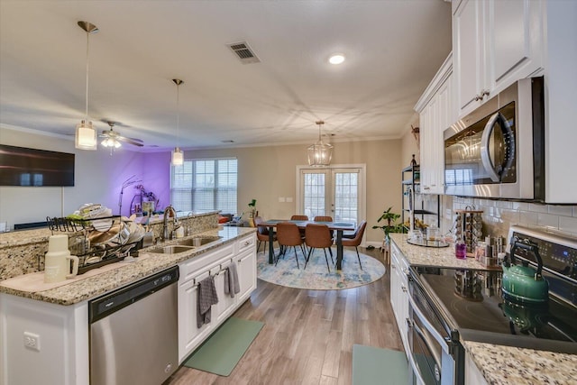 kitchen with white cabinetry, hanging light fixtures, stainless steel appliances, and sink