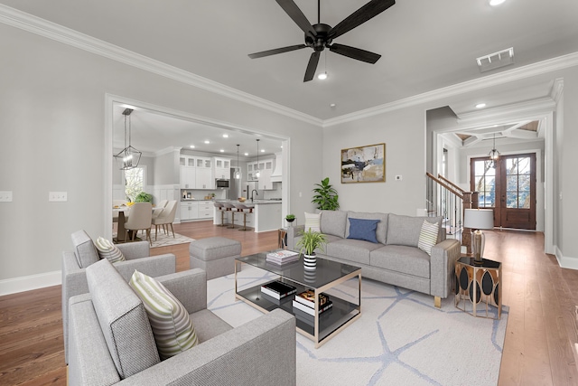 living room featuring ceiling fan, sink, french doors, hardwood / wood-style flooring, and ornamental molding