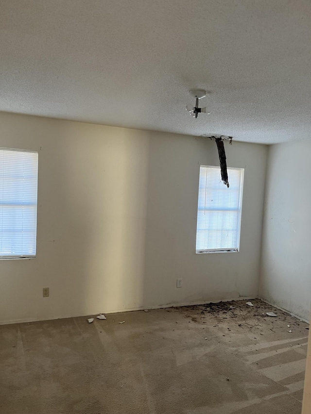 carpeted spare room with a textured ceiling