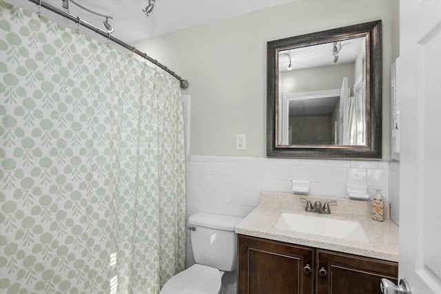 bathroom featuring vanity, toilet, and tile walls