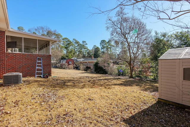 view of yard with central AC, a sunroom, and a storage unit