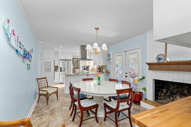 dining space with crown molding, a brick fireplace, a chandelier, and french doors