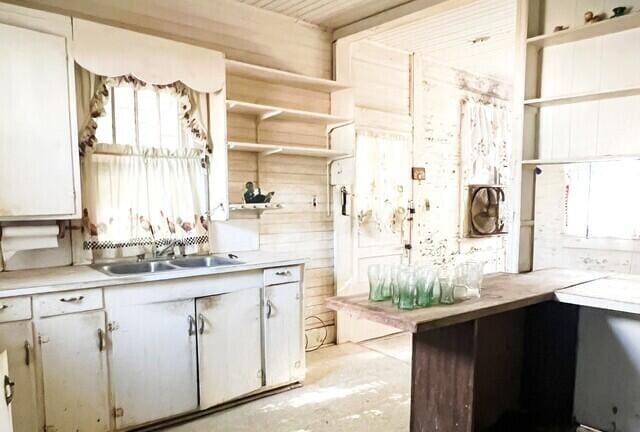 kitchen with sink, white cabinets, and wood walls