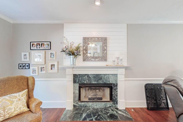 living area with crown molding, baseboards, wood finished floors, and a premium fireplace