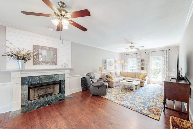 living room featuring crown molding, a ceiling fan, wood finished floors, and a high end fireplace
