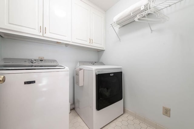 clothes washing area with baseboards, cabinet space, light tile patterned floors, and washer and dryer