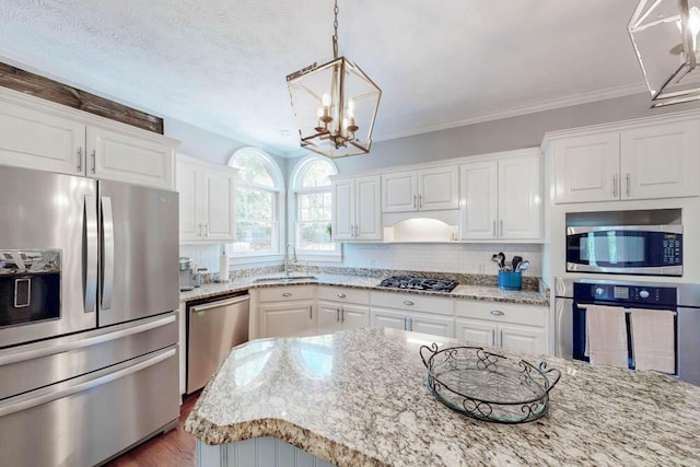 kitchen featuring a sink, stainless steel appliances, white cabinetry, and a notable chandelier