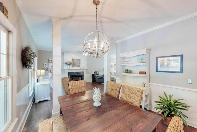 dining area with crown molding, wood finished floors, a fireplace, and an inviting chandelier