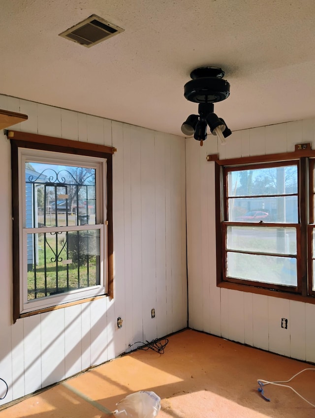 empty room with wood walls and a textured ceiling