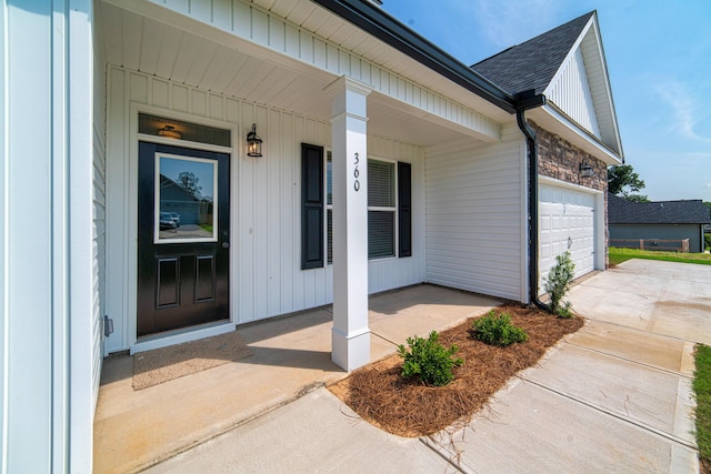 645 Jet Pass, Beech Island, SC 29842 - view of exterior entry featuring a porch, concrete driveway, a garage, roof with shingles, and stone siding