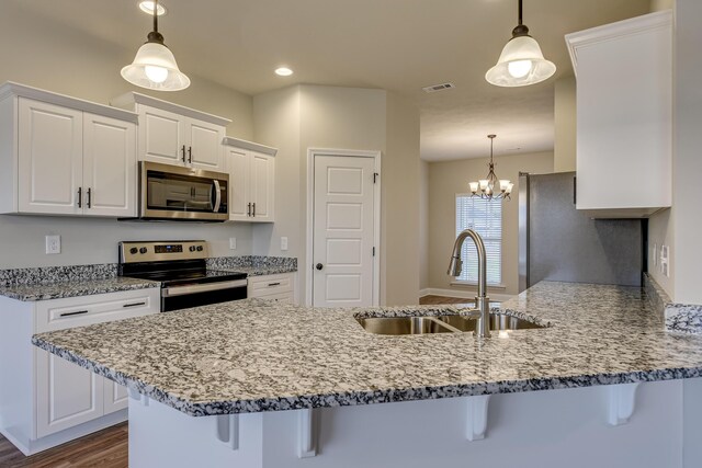 kitchen featuring white cabinetry, light stone countertops, an island with sink, and appliances with stainless steel finishes