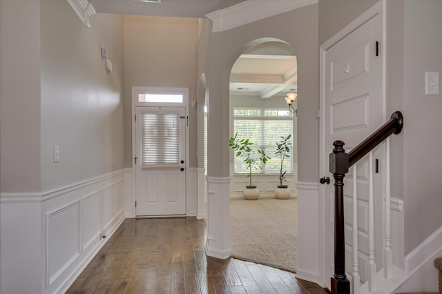 entryway with beamed ceiling, dark carpet, coffered ceiling, and ornamental molding