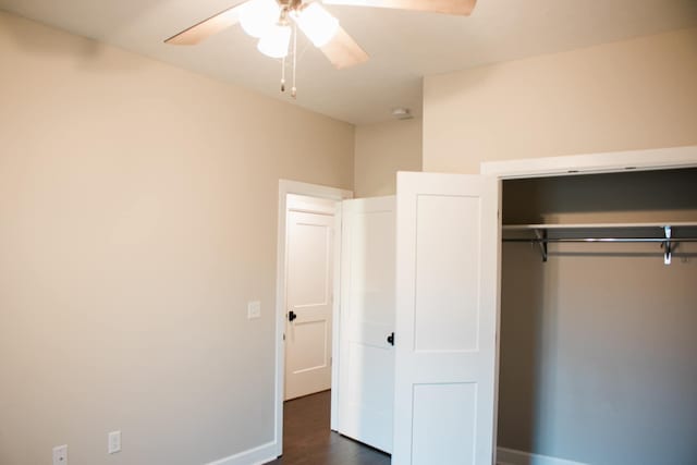 unfurnished bedroom with ceiling fan, dark wood-type flooring, a closet, and baseboards