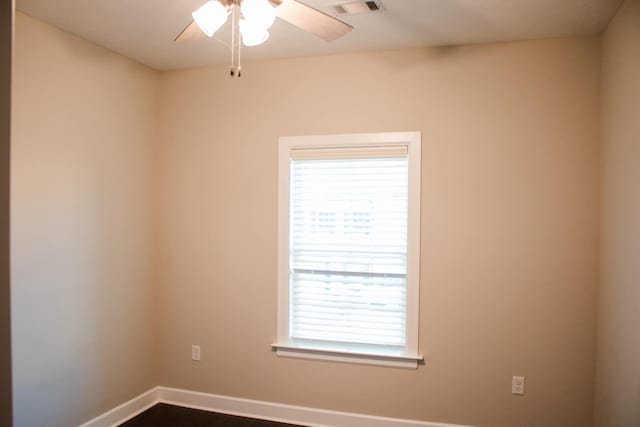 spare room featuring a ceiling fan, visible vents, and baseboards