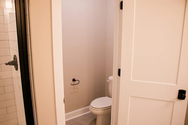 bathroom featuring a tile shower, tile patterned floors, toilet, and baseboards