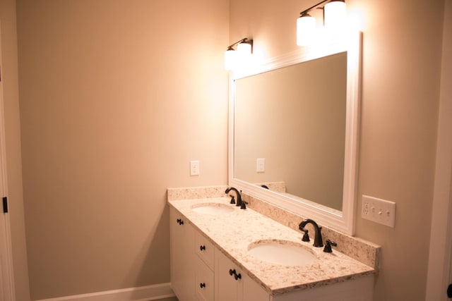 bathroom with a sink, baseboards, and double vanity