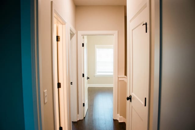 hall featuring dark wood-style flooring and baseboards