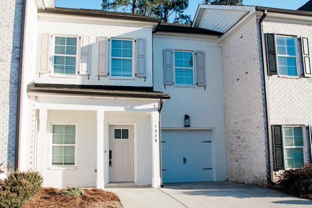 view of front facade with a garage, driveway, and brick siding