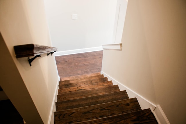 staircase with baseboards and wood finished floors