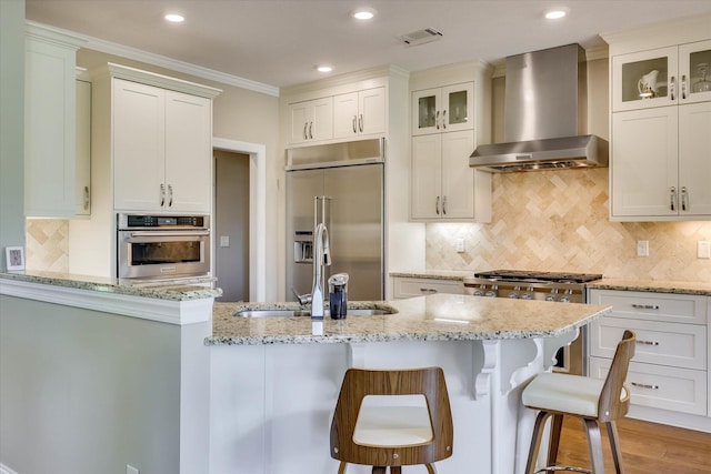 137 Elgin Ln, Mccormick, SC 29835 - kitchen with a breakfast bar area, glass insert cabinets, light stone counters, wall chimney exhaust hood, and stainless steel appliances