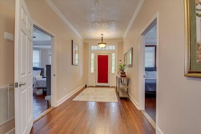 entrance foyer with a textured ceiling, hardwood / wood-style flooring, a wealth of natural light, and crown molding