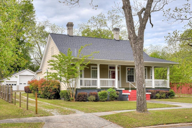 view of front facade featuring an outbuilding, a front lawn, covered porch, and a garage