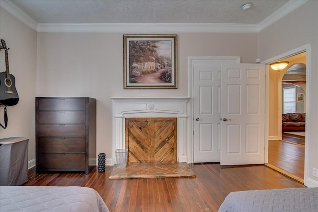 bedroom with a textured ceiling, dark hardwood / wood-style floors, and ornamental molding