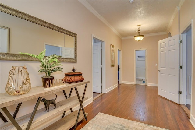 hall with hardwood / wood-style floors, a textured ceiling, and crown molding